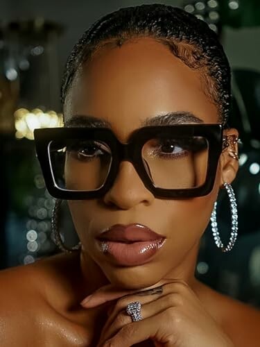 Woman wearing large square glasses and hoop earrings.