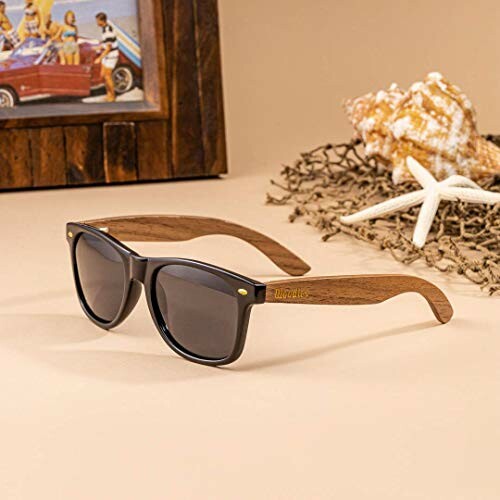 Sunglasses with wooden frames next to a starfish and seashell.